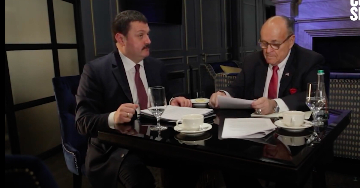 Andrii Derkach and Rudy Giuliani sit together at a table