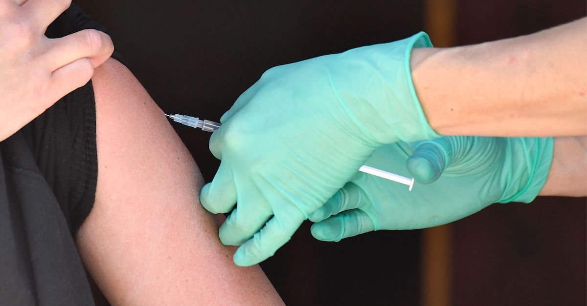 A medical assistant inserts into the arm the needle of a syringe containing the Johnson & Johnson Covid-19 vaccine.