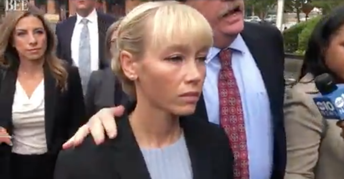 A woman in a business suit leaves court with her lawyer whose hand is on her shoulder