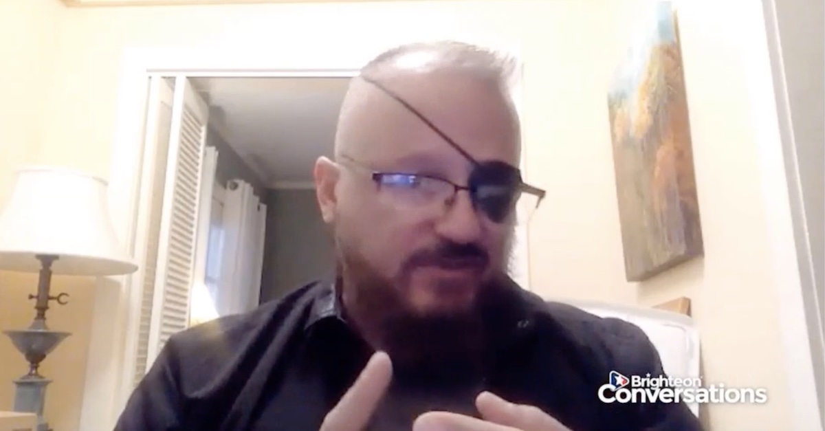 Stewart Rhodes, in glasses and and eyepatch, gives an interview to right-wing host Mike Adams.