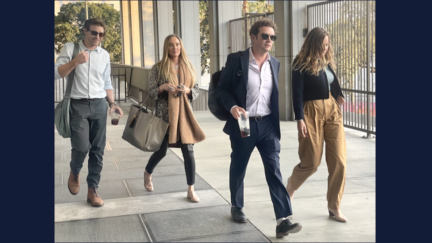 Four people walking out of a courthouse