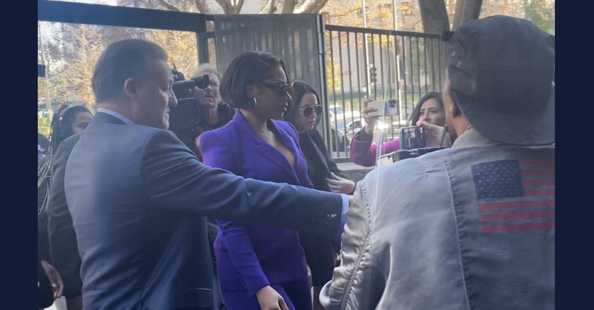 Megan Thee Stallion in a purple suit surrounded by security and media