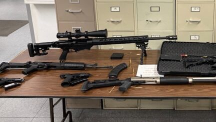 Several firearms and firearms parts are seen on a table.