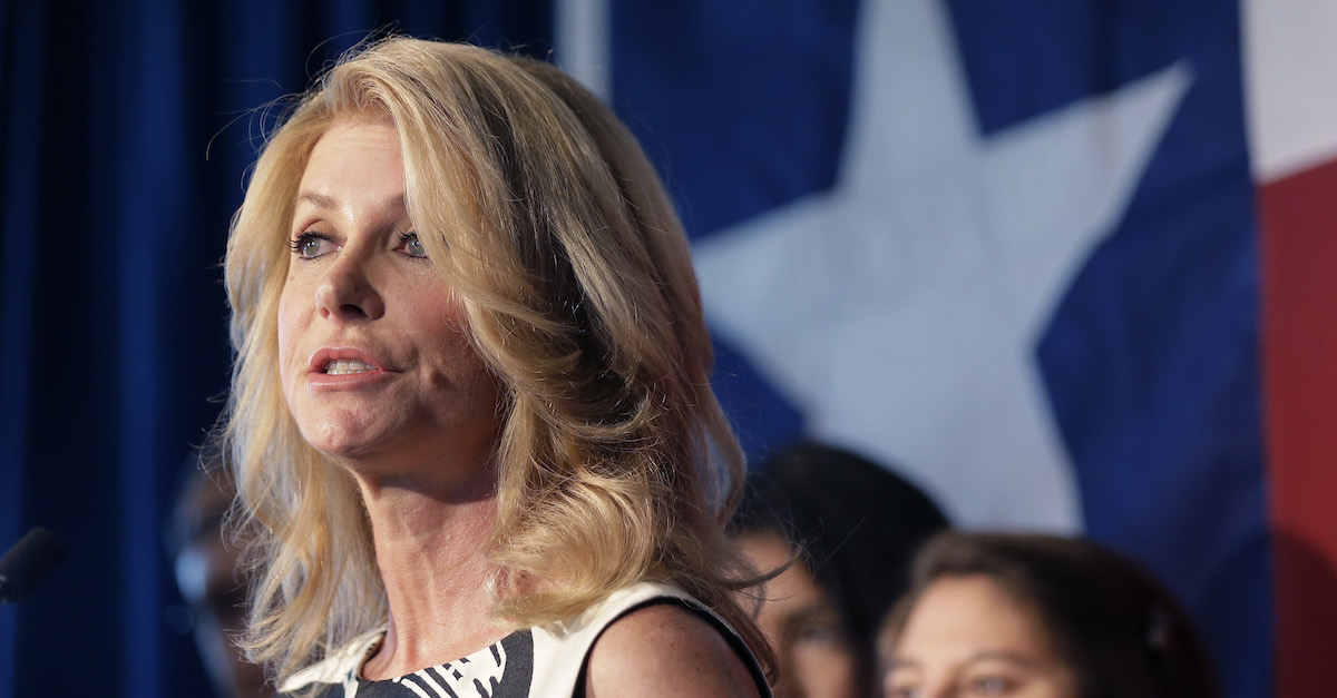 Wendy Davis is speaking while standing in front of the Texas flag.
