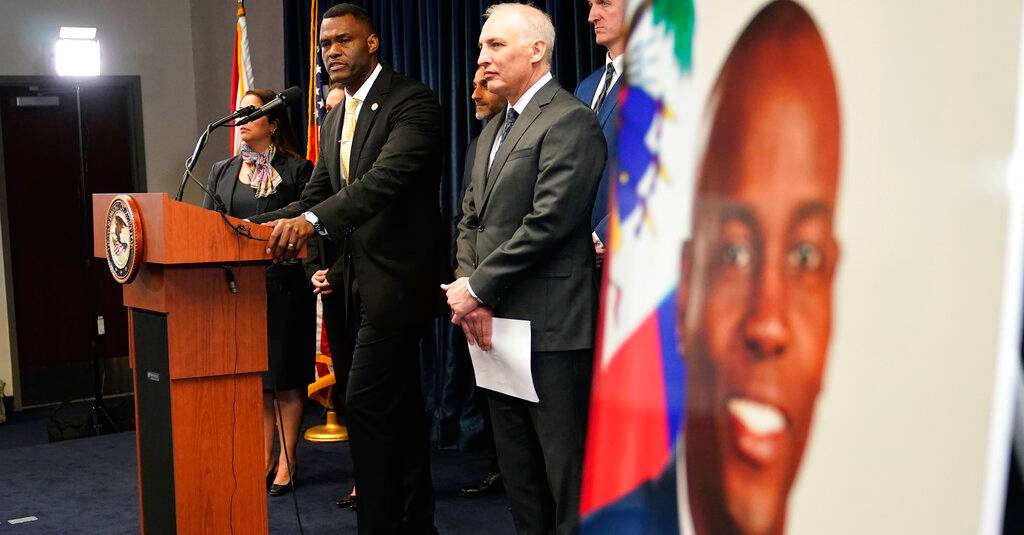 An image of Haitian President Jovenel Moïse, right, is displayed as Markenzy Lapointe, U.S. Attorney for the Southern District of Florida, left, speaks as Matthew Olsen, Assistant Attorney General for National Security, looks on during a news conference, Tuesday, Feb. 14, 2023, in Miami. U.S. authorities have arrested four more people in the slaying of Haitian President Jovenel Moïse, including the owner of a Miami-area security company that hired former soldiers from Colombia for the mission. (AP Photo/Lynne Sladky)