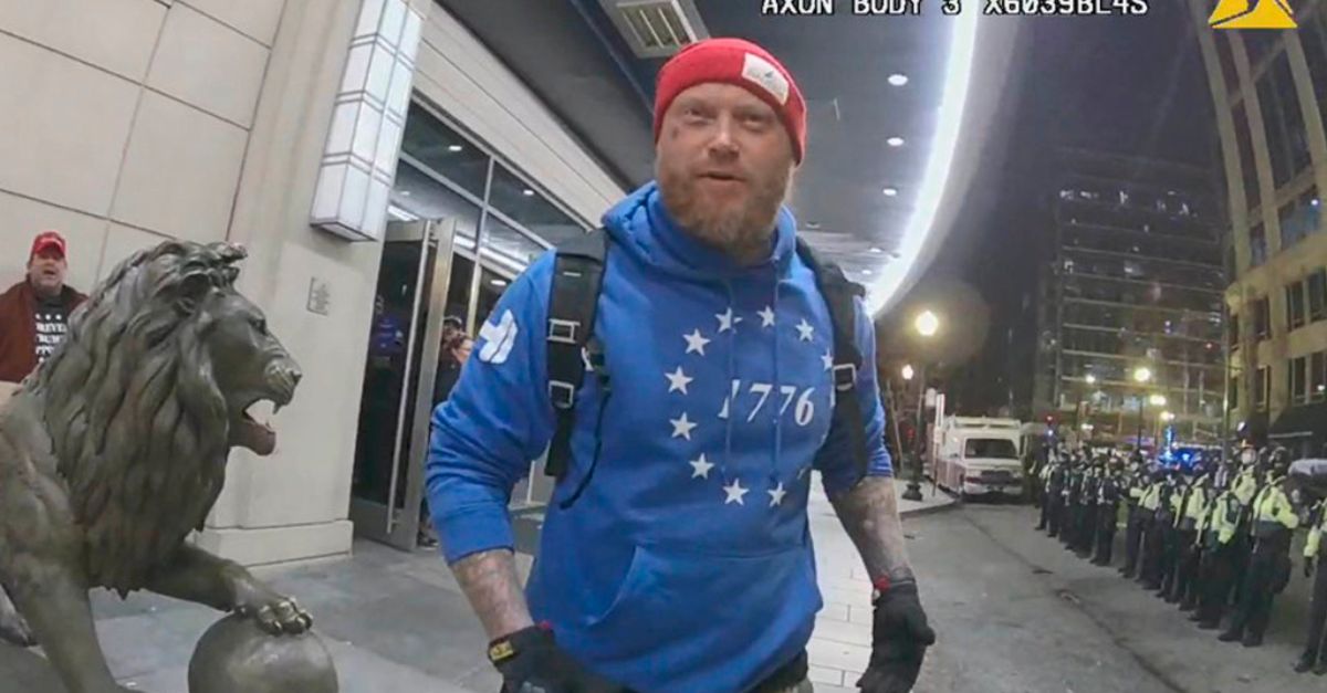 In this image from the body-worn camera of a Washington Metropolitan Police Department officer, released by the Justice Department in the Statement of Facts supporting an arrest warrant, Shane Jenkins confronts officers as they enforce a curfew outside the Embassy Suites Hotel, on Jan. 6, 2021, in Washington. Jenkins, a Texas man who attacked the U.S. Capitol with a metal tomahawk and is now the face of a website selling merchandise portraying jailed rioters as 